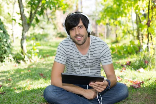 Young man relaxing with a tablet computer at a garden