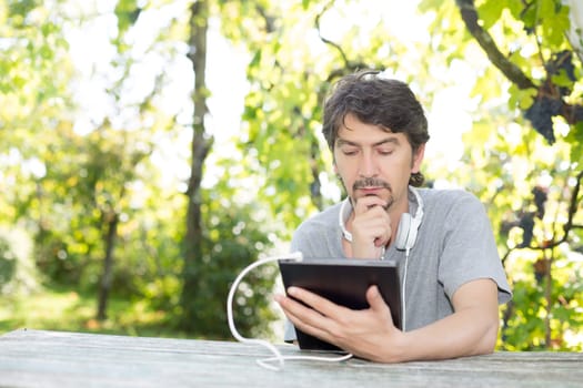 Young man relaxing with a tablet computer at a garden