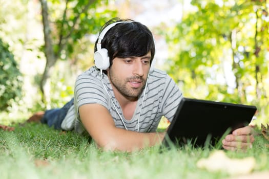 Young man relaxing with a tablet computer at a garden