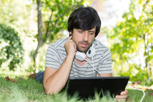 Young man relaxing with a tablet computer at a garden