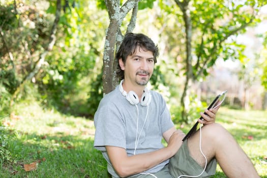 Young man relaxing with a tablet computer at a garden