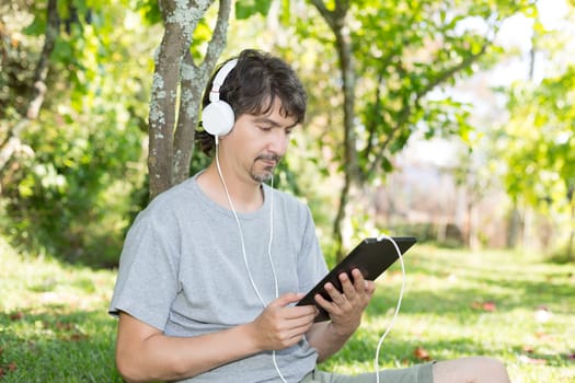 Young man relaxing with a tablet computer at a garden