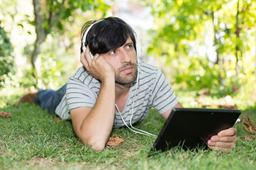 Young man relaxing with a tablet computer at a garden