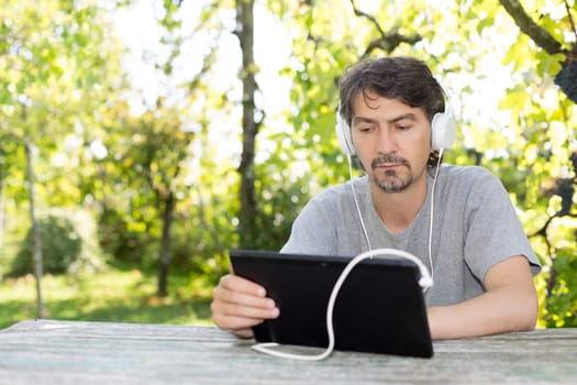 Young man relaxing with a tablet computer at a garden