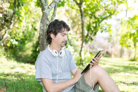 Young man relaxing with a tablet computer at a garden
