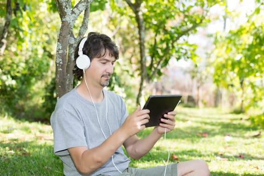 Young man relaxing with a tablet computer at a garden