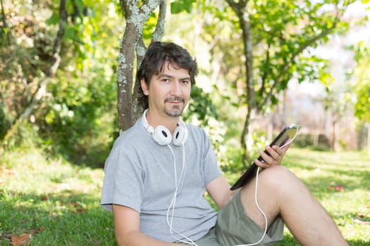 Young man relaxing with a tablet computer at a garden