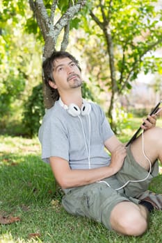 Young man relaxing with a tablet computer at a garden