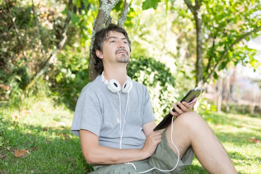 Young man relaxing with a tablet computer at a garden