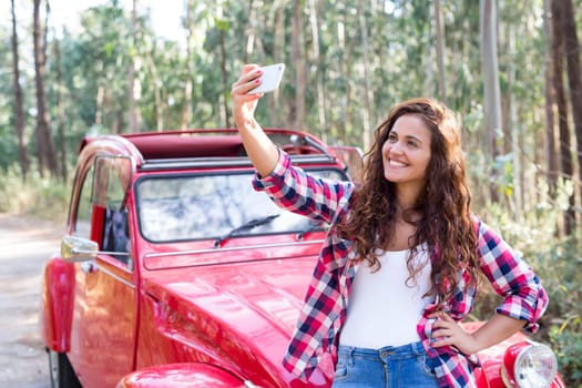 Young woman talking a selfie celebrating the start of a roadtrip