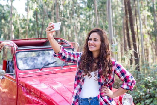 Young woman talking a selfie celebrating the start of a roadtrip
