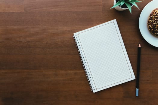 Donuts on the white plate and notebook on the wooden table. High quality photo