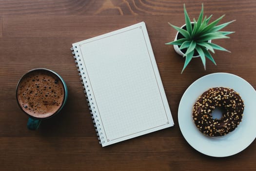 Donuts on the white plate, notebook and coffee on the wooden table. High quality photo