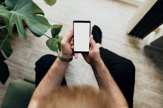 Man is holding smartphone with white screen. Blurred background. High quality photo