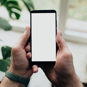Man is holding smartphone with white screen. High quality photo