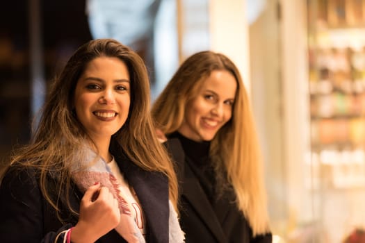 sale, consumerism and people concept - happy young women with shopping bags walking along city street