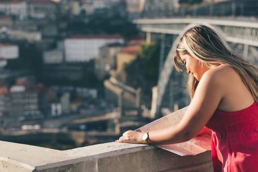 Young woman tourist enjoying beautiful landscape view on the old town with river and famous iron bridge during the sunset in Porto city, Portugal