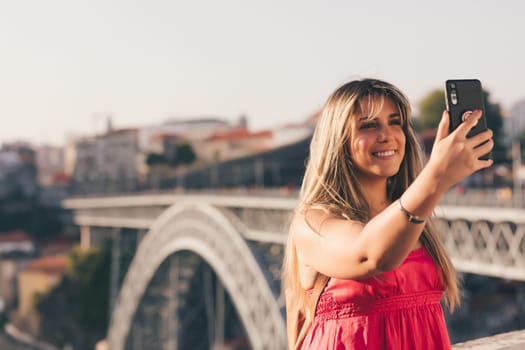 Young woman tourist enjoying beautiful landscape view on the old town with river and famous iron bridge during the sunset in Porto city, Portugal