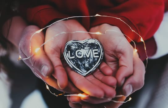 Hands holding stone heart with love text. Blurred background. High quality photo