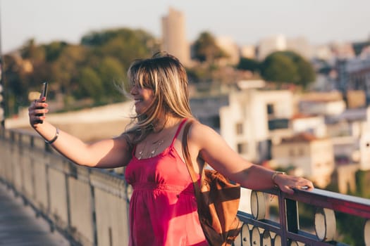 Young woman tourist enjoying beautiful landscape view on the old town with river and famous iron bridge during the sunset in Porto city, Portugal