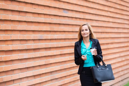Business woman with coffe and talking on the phone near office