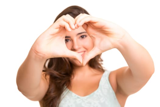 Beautiful woman making a heart shape with her hands, isolated over white background