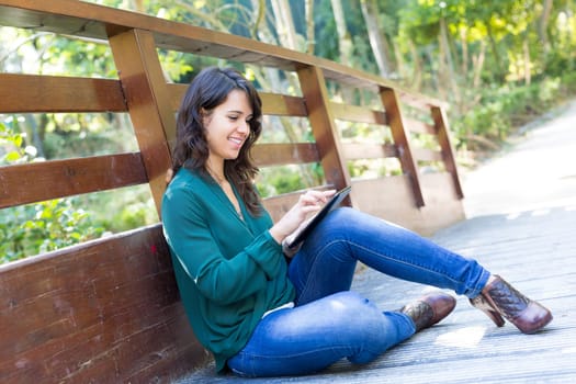Young woman relaxing at the park with a tablet computer