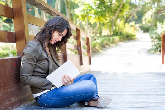 Young woman reading a book and relaxing at the park
