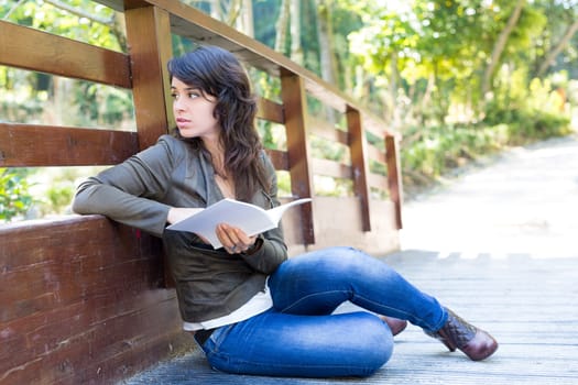 Young woman reading a book and relaxing at the park