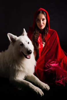 Woman wearing a red hood posing in studio with her dog