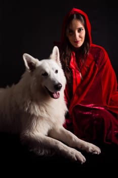 Woman wearing a red hood posing in studio with her dog