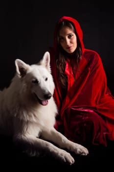 Woman wearing a red hood posing in studio with her dog