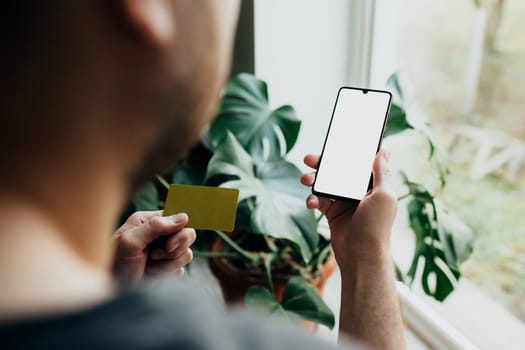Man holds smartphone with white screen and bank card. High quality photo