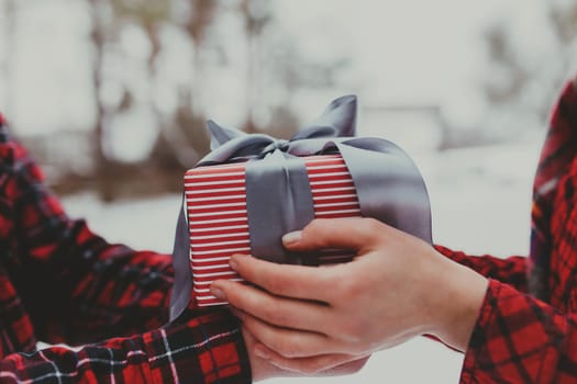 Hands giving a gift box with ribbon. Blurred background. High quality photo