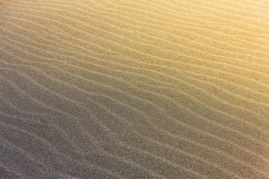 abstract wave line textures on a Pacific beach illuminated by the Sun and an empty quarter