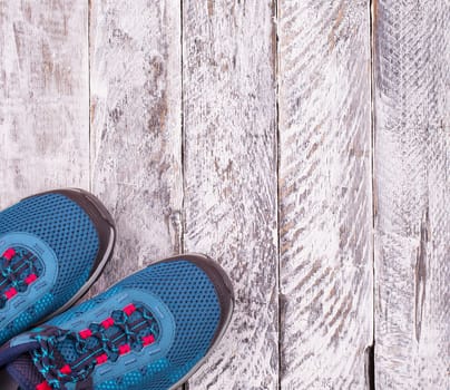 Pair of blue women's sneakers on white wooden surface