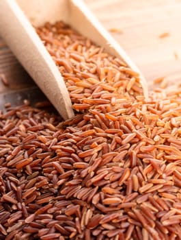 The raw brown rice with wooden spoon