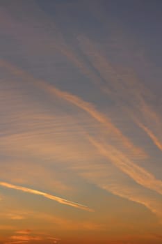 evening sky with red cirrus clouds with airplane trails