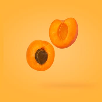 Minimal fruit concept. Two half apricot fruits with bone on bright yellow background with shadow. Design element. Full depth of field.