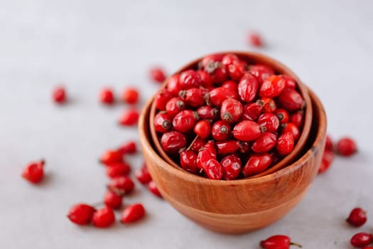 Medicinal plants and herbs. Rose hips berries in a wooden bowl on concrete background with copy space. Dried fruits for herbal teas and essential oils. Selective focus. Horizontal orientation.