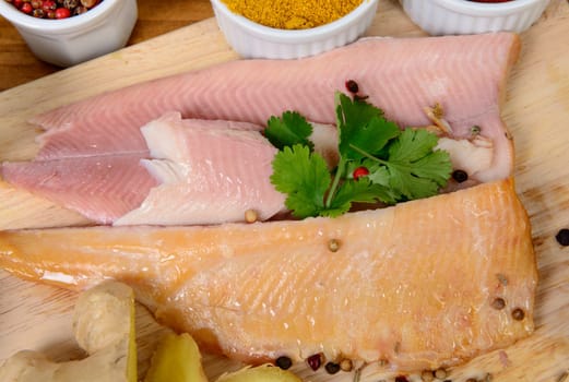 fish fillets on a wooden board with several spices