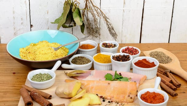 fish fillets with several spices on wooden table