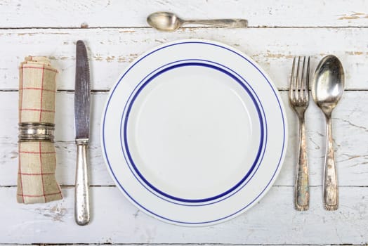 plate with silver cutlery on an old white table