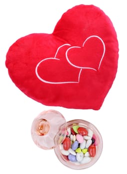 heart shaped cushion with candy on the white background