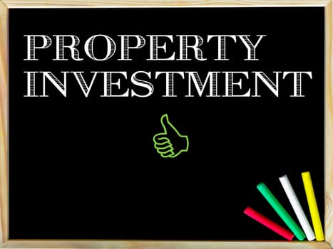 Property Investment message and Like sign.Handwriting with chalk on wooden frame blackboard, colored chalk in the corner, Business concept image
