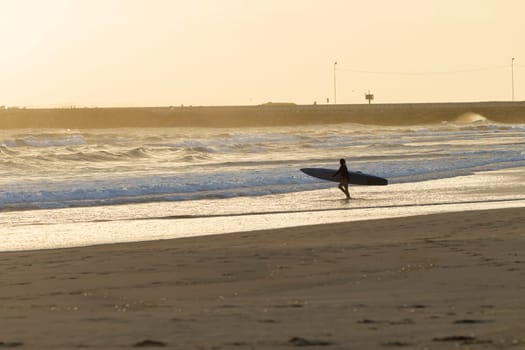 Teen girl athlete trains dawn sunrise on lifesaving rescue craft paddling out through ocean wave swells.