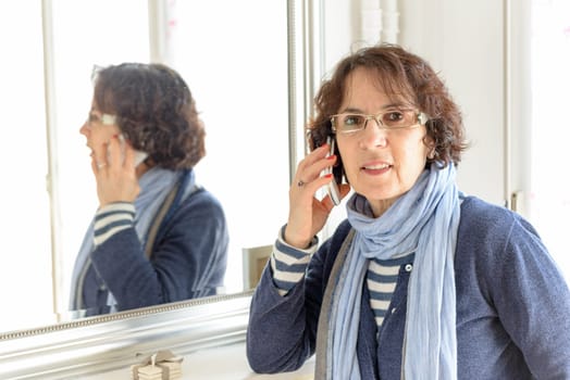 a senior woman phone near a mirror
