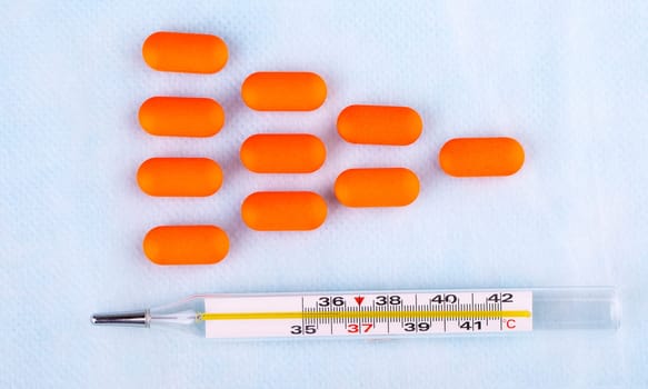 The pills in red packaging and thermometer on blur medical background
