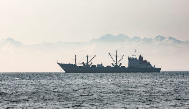 large fishing vessel on the background of hills and volcanoes