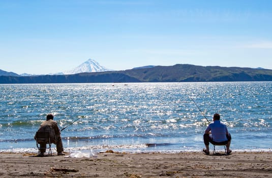 Fisherman sitting and fishing on the beach of Pacific ocean